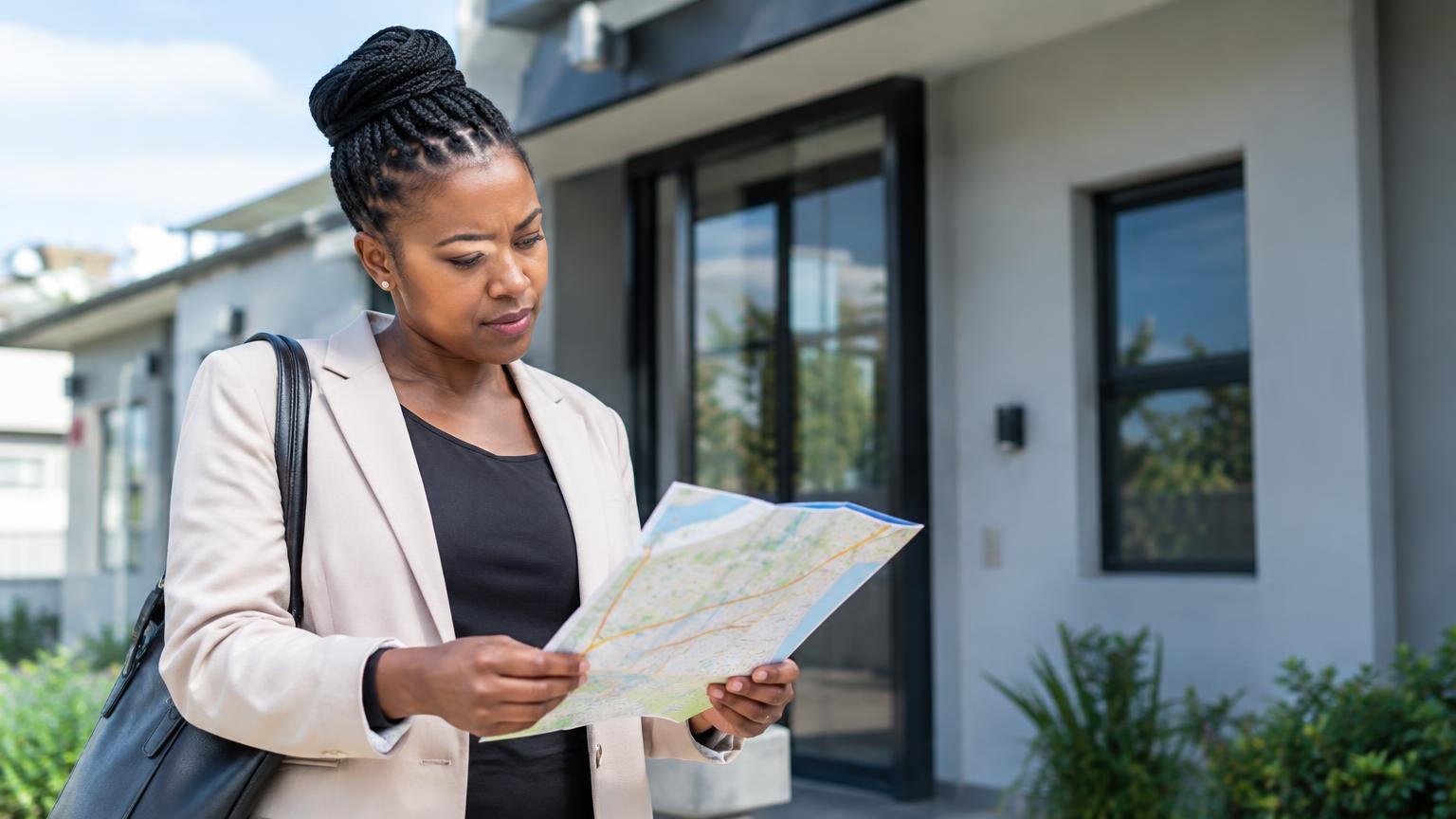 A business owner outside an office checking an abstract address map.