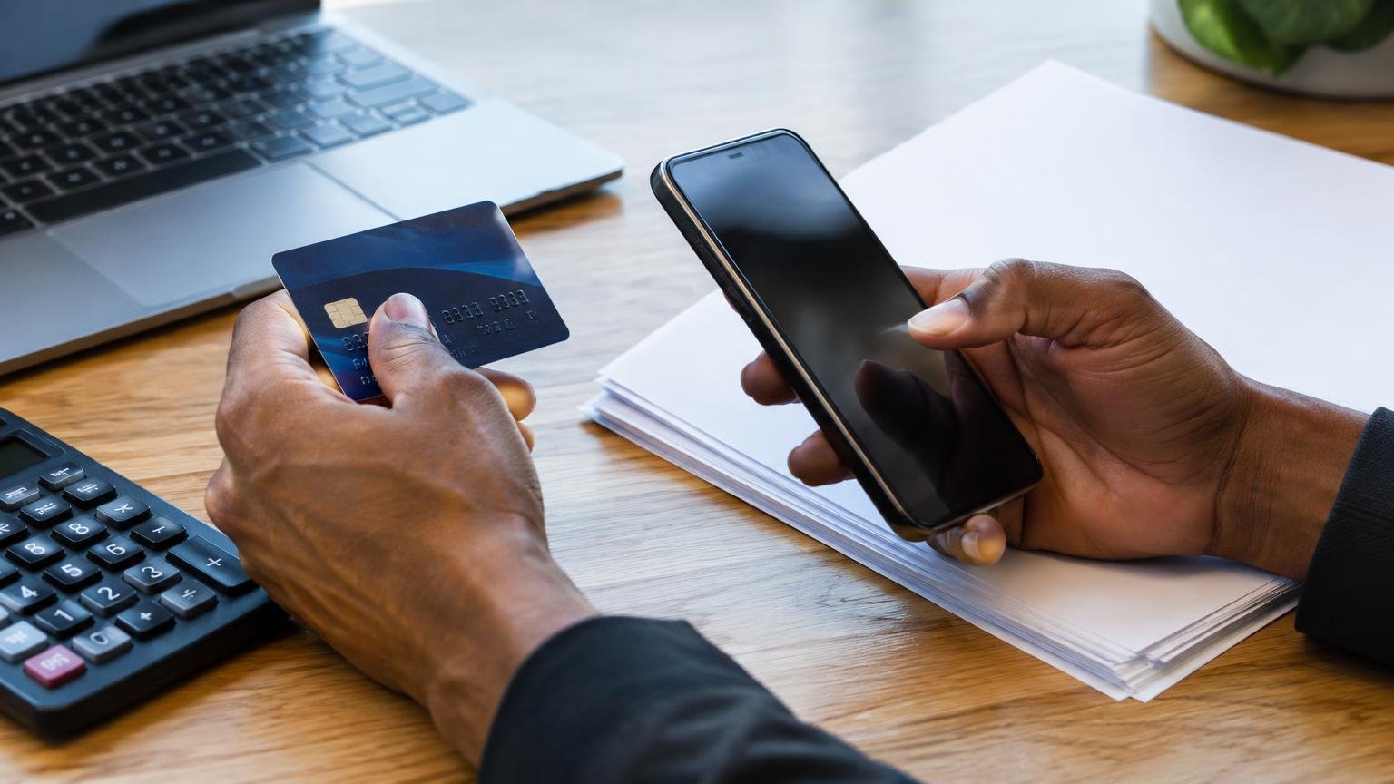 Hands checking a payment authorisation beside invoice papers.