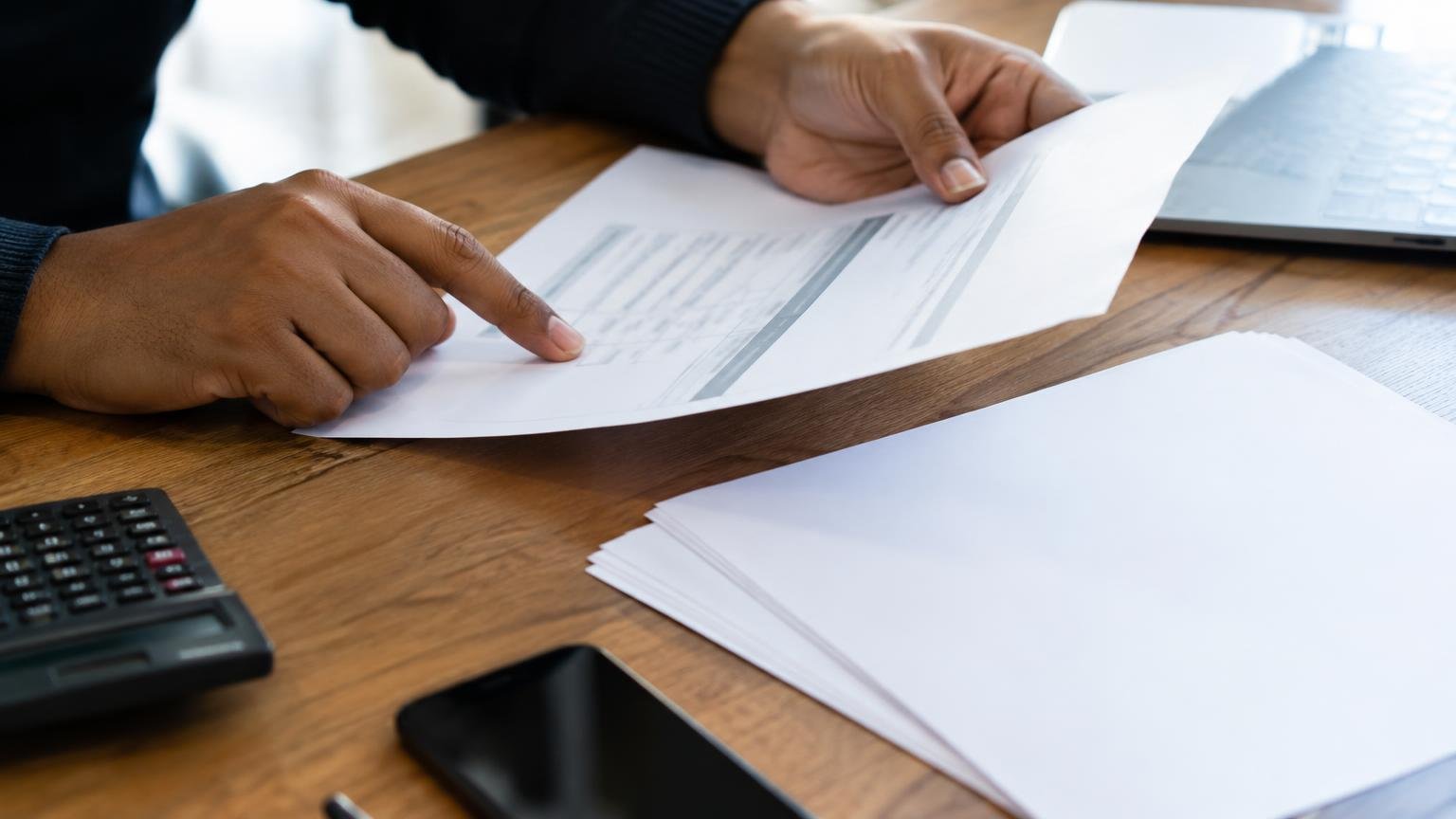 Hands checking a payment authorisation beside invoice papers.
